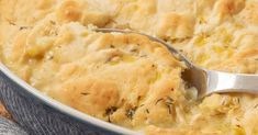 a close up of a spoon in a casserole dish with biscuits and cheese