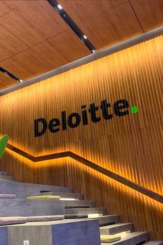 the deloitte logo is lit up on the wall above the stairs in this modern building