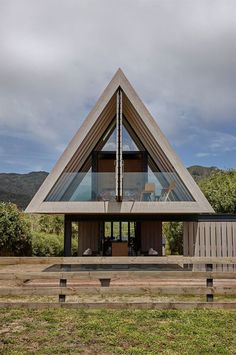 a triangular shaped house sitting on top of a lush green field