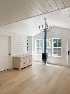 an empty room with white walls and wood flooring has a chandelier hanging from the ceiling