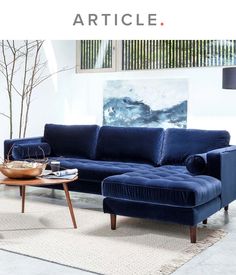 a living room with blue velvet furniture and article artwork on the wall above it