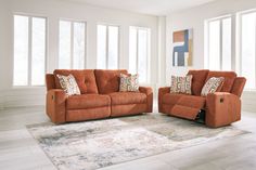 an orange couch and loveseat in a living room with white walls, rugs and windows