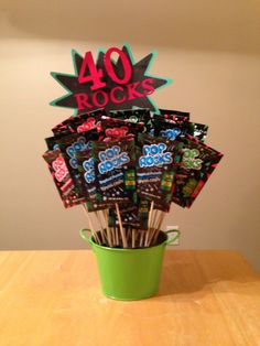 a green bucket filled with lots of candy on top of a wooden table next to a sign that says 40 rocks