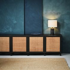 a lamp is sitting on top of a sideboard in a room with blue walls