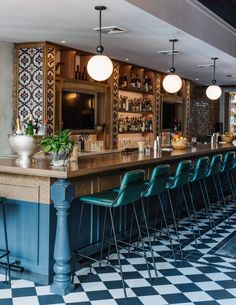 a bar with blue chairs and black and white checkered flooring in front of it