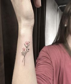 a woman's arm with a small flower tattoo on the left side of her wrist