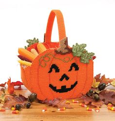 an orange pumpkin shaped basket filled with corn and carrots