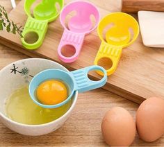 three eggs in measuring cups on a cutting board next to an egg slicer and two eggs