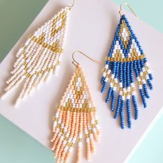 two pairs of beaded earrings sitting on top of a piece of white and blue paper