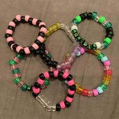 four bracelets with different colors and designs on them sitting next to each other in a pile