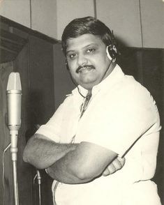 a man standing in front of a microphone with his arms crossed and headphones on