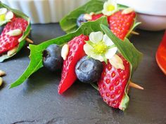 strawberries and blueberries are arranged on sticks