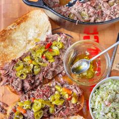 corned beef sandwich with coleslaw and pickles on cutting board next to bowl of salad