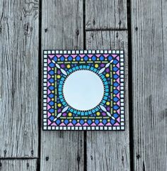 a small mirror sitting on top of a wooden floor next to a wall covered in wood planks