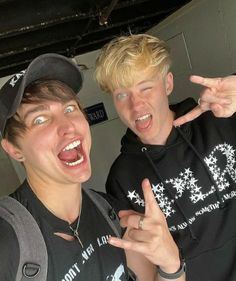 two young men posing for the camera with their hands in the air and one pointing