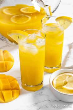 three glasses filled with orange juice on top of a table