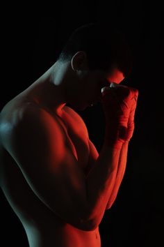 a shirtless man with boxing gloves on his face and hands in front of his face