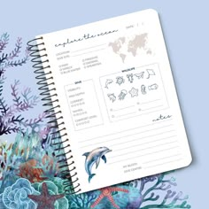 an open notebook with marine animals and plants on the cover, next to it is a blue background