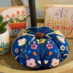 a blue pumpkin sitting on top of a wooden table next to potted plants and greeting cards