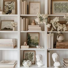 there are many books and vases on the shelves with flowers in them, along with other decorative items