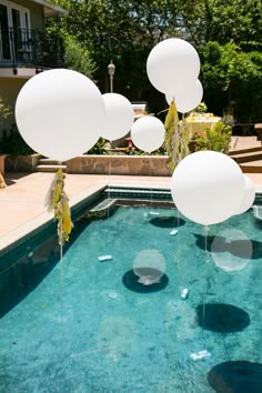 balloons floating in the air over a swimming pool