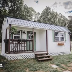 a small white house with a porch and steps leading up to the front door,