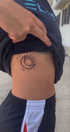 a woman's stomach with a small sun and moon tattoo on her lower back