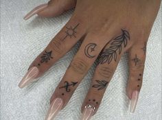 a woman's hand with tattoos on it and two fingers that have different designs