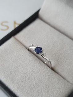 an engagement ring with a blue stone sits in a box