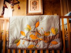 a baby crib with an orange and yellow tree on it