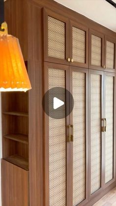 a large wooden cabinet with glass doors in a living room next to a wall lamp