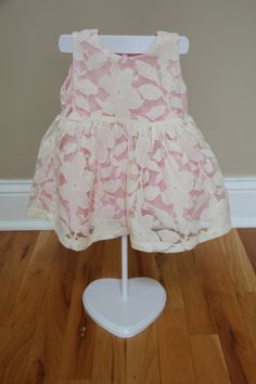 a pink dress on a mannequin stand in front of a wall and hardwood floor