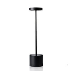 a black table lamp with a round base on a white background, it appears to be in the middle of an empty room