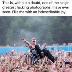 a man in a wheelchair with his arms raised up to the sky, surrounded by people