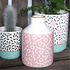 three vases with plants in them sitting on a wooden table next to each other