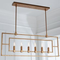 a rectangular chandelier with candles hanging from it's sides in a room