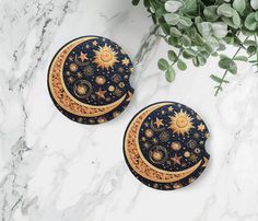 two black and gold plates sitting on top of a white marble table next to a potted plant