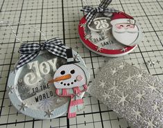 three christmas ornaments sitting on top of a cutting board next to scissors and paper machs