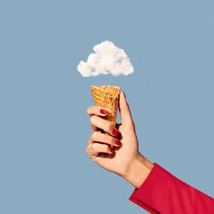 a hand holding an ice cream cone with a cloud in it