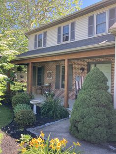 a house that has some flowers in front of it and bushes around the back yard