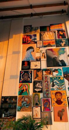 a wall covered in pictures and paintings next to a potted plant