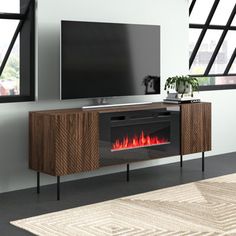 an entertainment center with a fireplace in the middle and windows on both sides, along with a rug