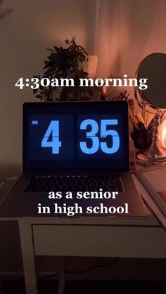 an open laptop computer sitting on top of a desk next to a lamp and clock