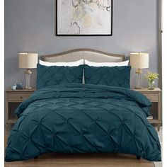 a bed with blue comforter and two lamps on the nightstands next to it