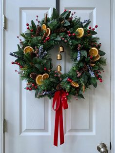 a christmas wreath with oranges and berries hanging on a door