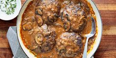 some meatballs and mushrooms in gravy on a wooden table