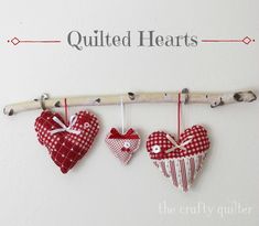 three heart shaped ornaments hanging from a clothes line with the words quilted hearts above them