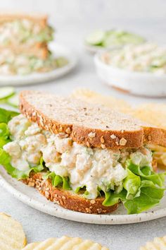 a chicken salad sandwich with lettuce and crackers on the side, ready to be eaten