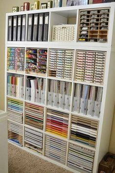 a book shelf filled with lots of books and binders on top of carpeted floor