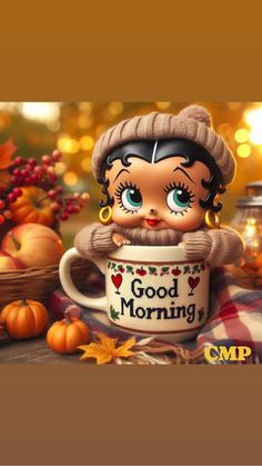 a doll is holding a coffee cup with the words good morning on it and pumpkins around